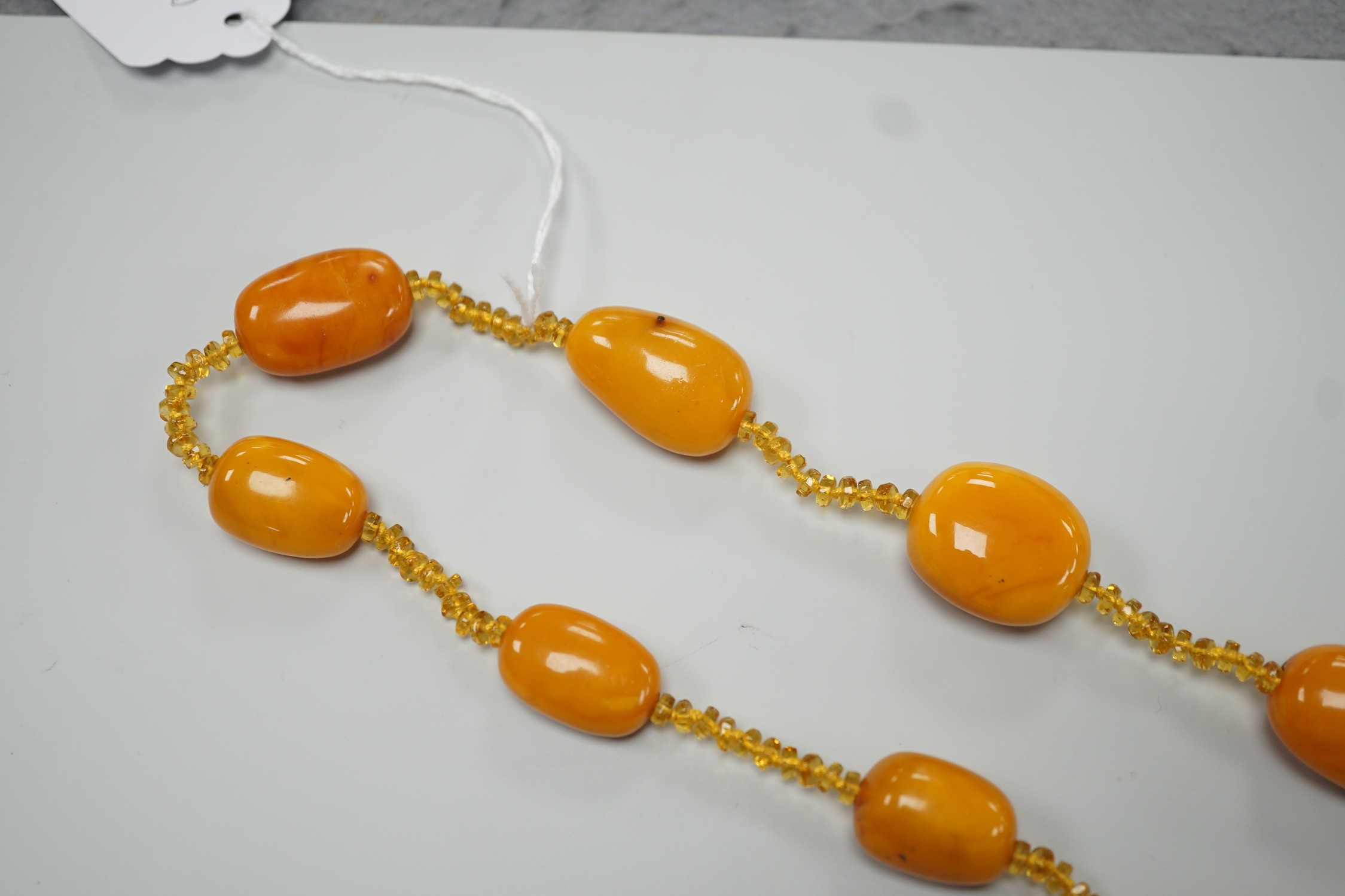 A single strand graduated fifteen amber bead necklace, with multiple amber? spacers, 84cm, gross weight 89 grams.